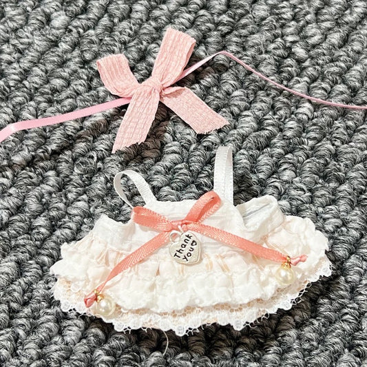 White lace baby booties with pink ribbons on a textured gray surface