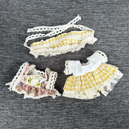 Set of miniature lace dresses on a textured fabric background