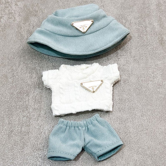 Baby outfit set with white top, blue shorts, and light blue hat on a gray surface